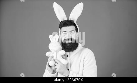 Konzept des Ostersymbols. Kerl bärtiger Flusspferd süßer sanfter, bunter langer Ohren blauer Hintergrund. Respekt vor Traditionen. Osterhase. Mann trägt einen kuscheligen Plüschanzug. Lustiger Hünenmann mit Bart und Schnurrbart. Stockfoto