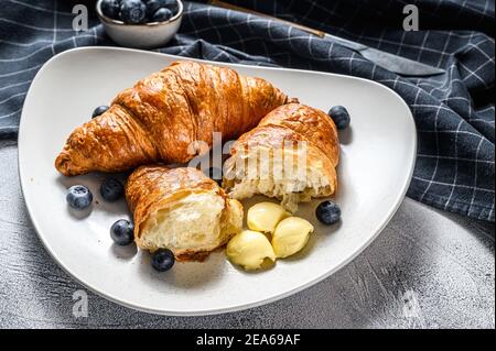 Frische Croissants, Butter und Heidelbeeren. Leckeres Frühstück. Grauer Hintergrund. Draufsicht Stockfoto