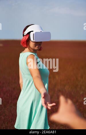 Frau geht in die virtuelle Realität mit Virtual-Reality-Headset. Das Konzept der virtuellen Realität, Simulationen, Verbindung und Kommunikation. Stockfoto