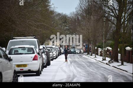 Brighton UK 8th February 2021 - EIN Läufer stampft die verschneiten Straßen rund um den Queens Park in Brighton nach einem leichten Schneefall über Nacht mit weiteren Prognosen für Teile des Ostens und Südostens heute: Credit Simon Dack / Alamy Live News Stockfoto