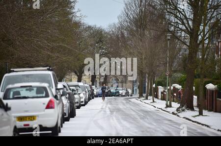 Brighton UK 8th February 2021 - EIN Läufer stampft die verschneiten Straßen rund um den Queens Park in Brighton nach einem leichten Schneefall über Nacht mit weiteren Prognosen für Teile des Ostens und Südostens heute: Credit Simon Dack / Alamy Live News Stockfoto