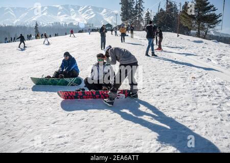 Snowboarder ruhen auf einer schneebedeckten Piste in einem berühmten Skigebiet in Gulmarg. Gulmarg ist eine Stadt, eine Bergstation, ein beliebtes Skiziel und ein mitteiltes Gebietskomitee im Baramulla Distrikt Jammu und Kaschmir. Die Stadt liegt in der Pir Panjal Range im westlichen Himalaya und liegt innerhalb der Grenzen des Gulmarg Wildlife Sanctuary. Stockfoto