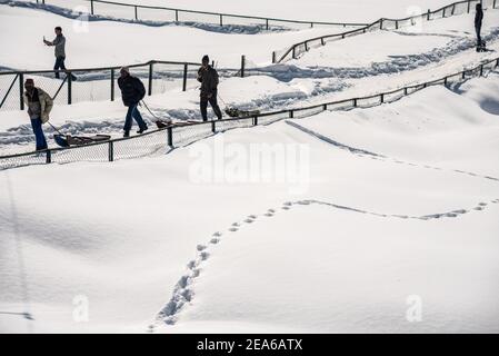 Arbeiter ziehen Schlitten mit Touristen in den Wiesen von Gulmarg. Gulmarg ist eine Stadt, eine Bergstation, ein beliebtes Skiziel und ein mitteiltes Gebietskomitee im Baramulla Distrikt Jammu und Kaschmir. Die Stadt liegt in der Pir Panjal Range im westlichen Himalaya und liegt innerhalb der Grenzen des Gulmarg Wildlife Sanctuary. Stockfoto