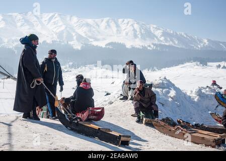 Schlittenbesitzer warten auf Kunden in einem berühmten Skigebiet in Gulmarg. Gulmarg ist eine Stadt, eine Bergstation, ein beliebtes Skiziel und ein mitteiltes Gebietskomitee im Baramulla Distrikt Jammu und Kaschmir. Die Stadt liegt in der Pir Panjal Range im westlichen Himalaya und liegt innerhalb der Grenzen des Gulmarg Wildlife Sanctuary. Stockfoto