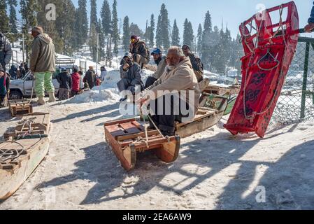 Schlittenbesitzer warten auf Kunden in einem berühmten Skigebiet in Gulmarg. Gulmarg ist eine Stadt, eine Bergstation, ein beliebtes Skiziel und ein mitteiltes Gebietskomitee im Baramulla Distrikt Jammu und Kaschmir. Die Stadt liegt in der Pir Panjal Range im westlichen Himalaya und liegt innerhalb der Grenzen des Gulmarg Wildlife Sanctuary. Stockfoto
