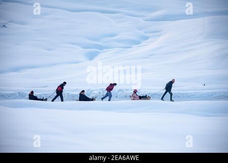 Arbeiter ziehen Schlitten mit Touristen in den Wiesen von Gulmarg. Gulmarg ist eine Stadt, eine Bergstation, ein beliebtes Skiziel und ein mitteiltes Gebietskomitee im Baramulla Distrikt Jammu und Kaschmir. Die Stadt liegt in der Pir Panjal Range im westlichen Himalaya und liegt innerhalb der Grenzen des Gulmarg Wildlife Sanctuary. Stockfoto