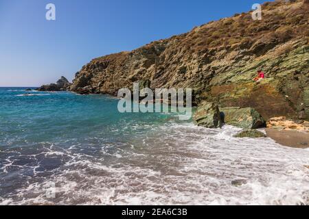 Insel Folegandros, Griechenland - 25. September 2020: Blick auf die Küste und den felsigen Ampeli Strand der Insel Folegandros. Die Leute sonnen sich auf dem Be Stockfoto