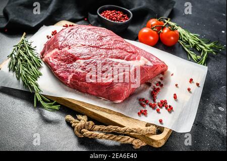 Rohes Rindfleisch auf einem Holzschneidebrett geschnitten. Schwarzes Angus-Rindfleisch. Schwarzer Hintergrund. Draufsicht Stockfoto