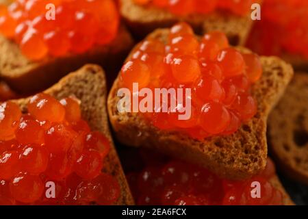 Brotscheiben mit rotem Kaviar auf dem ganzen Hintergrund, Nahaufnahme Stockfoto