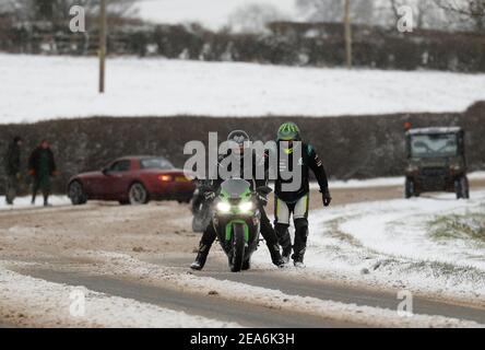 Uppingham, Rutland, Großbritannien. 8th. Februar 2021. Wetter in Großbritannien. Ein Motorradfahrer schiebt einen Mitfahrer auf einen Schnee- und eisbedeckten Hügel. Credit Darren Staples/Alamy Live News. Stockfoto