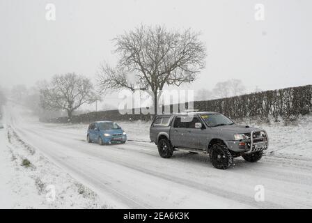 Uppingham, Rutland, Großbritannien. 8th. Februar 2021. Wetter in Großbritannien. Ein Fahrer aus Leicestershire und Rutland 4x4 Response zieht einen gestrandeten Autofahrer auf einen Schnee- und eisbedeckten Hügel. Credit Darren Staples/Alamy Live News. Stockfoto