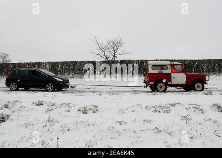 Uppingham, Rutland, Großbritannien. 8th. Februar 2021. Wetter in Großbritannien. Ein Fahrer aus Leicestershire und Rutland 4x4 Response zieht einen gestrandeten Autofahrer auf einen Schnee- und eisbedeckten Hügel. Credit Darren Staples/Alamy Live News. Stockfoto