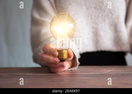 Weibliche Hand hält eine glänzende Glühbirne, große Idee, Innovation und Inspiration, Geschäftskonzept Hintergrund Stockfoto