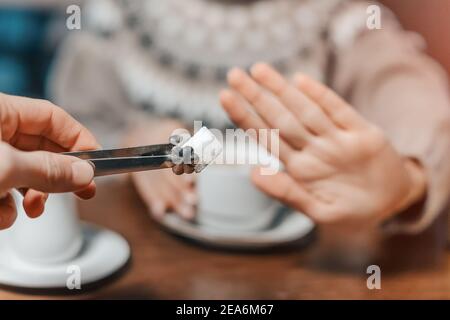 Eine Frau in einem Café lehnt ein Stück weißen Zucker für ihren Tee ab. Sagen Sie Nein zu Zucker und schnelle Kohlenhydrate. Diät für Diabetes und sucht nach süßen Junk-Food Stockfoto