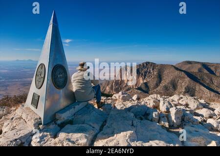 Wanderer am Gipfelschild auf Guadalupe Peak, Chihuahuan Desert below, Guadalupe Mountains National Park, Texas, USA Stockfoto