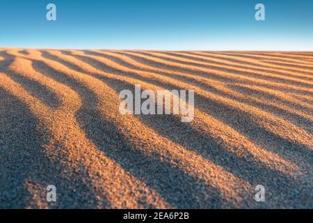 Nahaufnahme Textur der gewellten Oberfläche von Sand und Dünen, Draufsicht. Wüstenhintergrund Stockfoto