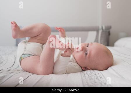 Ein süßes Baby, das auf einem riesigen Bett mit Weiß schläft Blätter Stockfoto