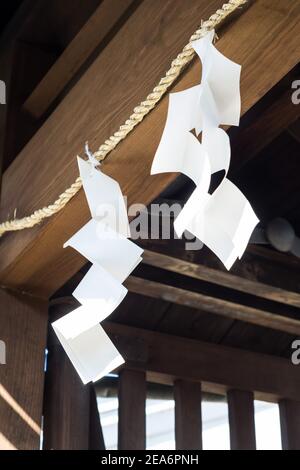 Zwei weiße Shide, Zickzack-förmige Papierstreamer, verwendet für Reinigung und Segen in Shinto Zeremonien, hängend von einem Schreineingang in Nara, Japan Stockfoto