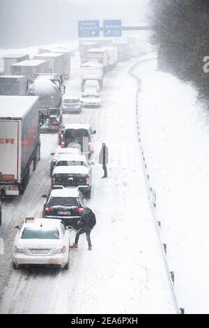 Oberhausen, Deutschland. Februar 2021, 08th. Fahrzeuge stecken auf der Autobahn A2/A3 am Kreuz Oberhausen in einem Stau fest. Die Leute steigen aus ihren Autos und stehen auf der Autobahn. Der starke Schneefall in Nordrhein-Westfalen verursacht schwere Verkehrsbeschränkungen. Quelle: Fabian Strauch/dpa/Alamy Live News Stockfoto