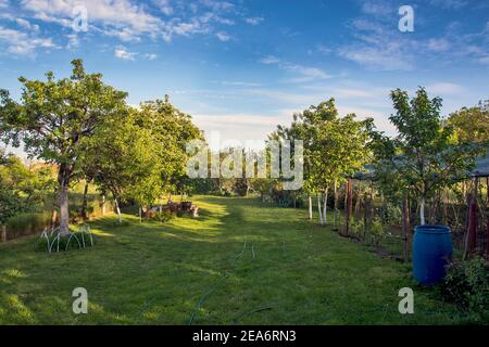 Arrangiert und schöner Dorfhof mit Gras. Der Hof sieht besonders schön aus, während er von der untergehenden Abendsonne beleuchtet wird. Stockfoto