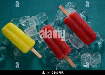 Erdbeerpopsicle und Zitronenpopsicle auf blauem Hintergrund mit Eis Stockfoto