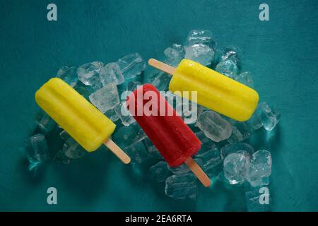 Erdbeerpopsicle und Zitronenpopsicle auf blauem Hintergrund mit Eis Stockfoto