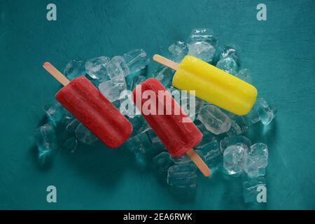 Erdbeerpopsicle und Zitronenpopsicle auf blauem Hintergrund mit Eis Stockfoto
