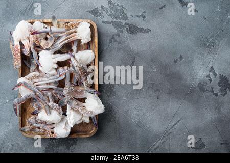 Gefrorenes rohes blaues schwimmende Krabbenfleisch, auf Holztablett, auf grauem Hintergrund, Draufsicht flach liegend, mit Copyspace und Platz für Text Stockfoto