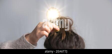 Junge Frau hält Glühbirne über Kopf in ihrer Hand, Kreativität, Geschäft, Lösung, Denken, Ideen Konzept, kopieren Raum Stockfoto