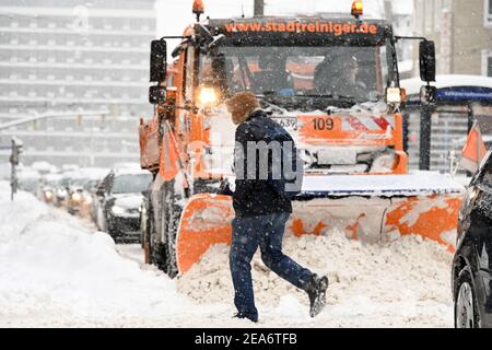 Kassel, Deutschland. Januar 2021, 08th. Ein Mann überquert die Straße vor einem Schneepflug. Der Wintereinbruch mit Eis und Schnee hat am Montag den Norden und Osten Hessens dominiert. Quelle: Uwe Zucchi/dpa/Alamy Live News Stockfoto