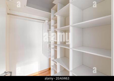 Innen von kleinen, weißen und leeren Ankleideraum mit Regalen und keine Kleidung. Stockfoto