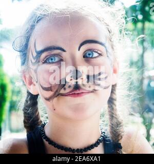 Nahaufnahme Porträt eines lächelnden Mädchen mit Tiger Gesichtsfarbe stehen in einem Garten, Italien Stockfoto