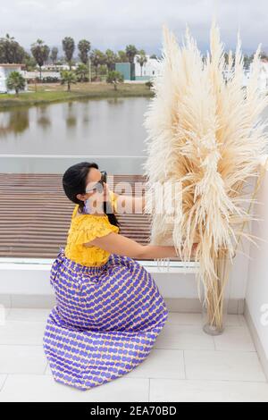 Nette lateinische Frau genießt die Anordnung ihrer Pampas Gras Blumenarrangement Stockfoto