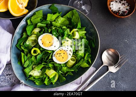 Schüssel Spinatsalat mit Gurke, Eiern und Sesamsamen und Orangenkeilen Stockfoto