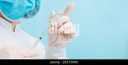 Arzt macht die Impfung in Schutzmaske und Handschuhe. Covid 19 Impfstoff in Glasfläschchen Flasche und Spritze, Medizin Flüssigkeit in Arzt Hand für Stockfoto