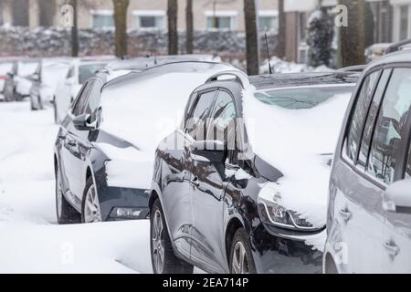 Autos in einer Straße in einem modernen Vorort bedeckt geparkt Mit Schnee nach einem Schneesturm Stockfoto