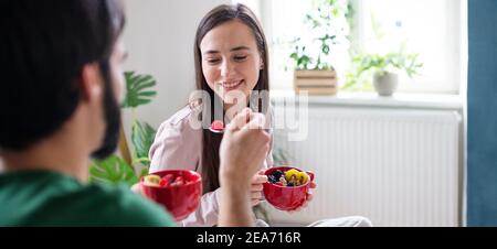 Junges Paar in der Liebe essen gesundes Frühstück auf dem Bett drinnen zu Hause. Stockfoto