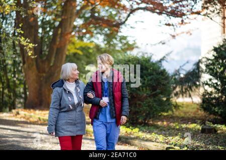 Ältere Frau und Betreuer im Freien auf einem Spaziergang im Park, reden. Stockfoto