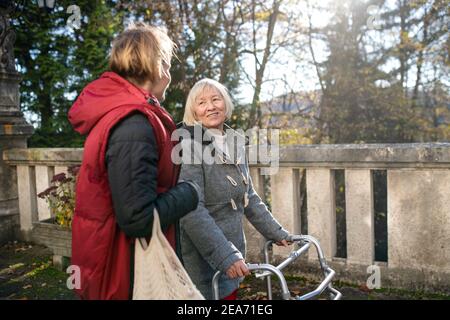 Ältere Frau mit Gehrahmen und Betreuer im Freien auf einem Spaziergang im Park. Stockfoto