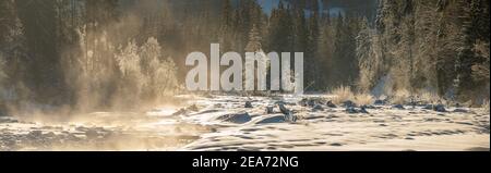 Winterlandschaftspanorama - Alpenfluss und Wald auf an Extrem kalter Wintermorgen Stockfoto