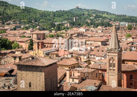 Eine Luftaufnahme der alten Gebäude der Stadt Und Dächer von Bologna Italien mit dem Heiligtum der Madonna di San Luca auf einem Hügel in der Ferne Stockfoto