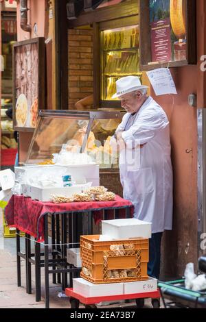 Mann, der Käse und Essen in einer engen Straße verkauft Bologna Italien Stockfoto