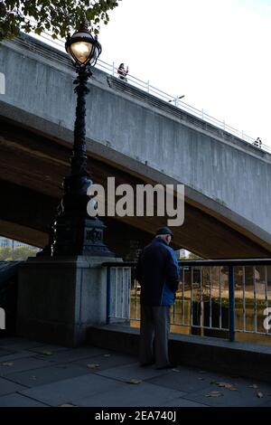 LONDON - OKTOBER 2018: Ein älterer Herr steht auf der South Bank in London und blickt auf die Themse und die Waterloo Bridge. Stockfoto