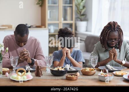 Porträt der modernen afroamerikanischen Familie sagen Gnade am Esstisch, während Ostern zu Hause feiern, kopieren Raum Stockfoto