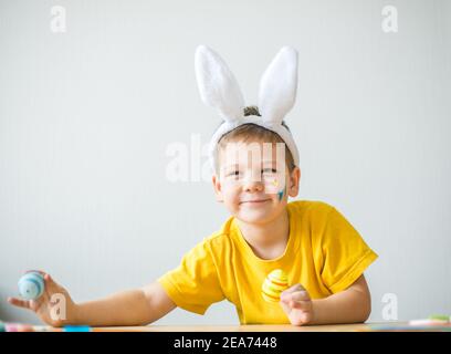 Portrait von lächelnden Jungen mit Hasen Ohren halten farbige Eier für Ostern in Kunststudio, Kopierer Raum. Vorbereitung auf Ostern. Stockfoto