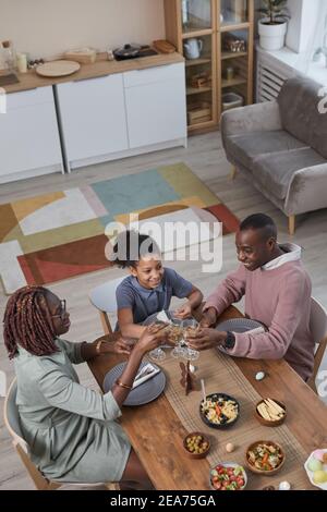 Vertikales Hochwinkelporträt der modernen afrikanisch-amerikanischen Familie, die zusammen Abendessen genießt, während sie Ostern zu Hause feiert, Kopierraum Stockfoto