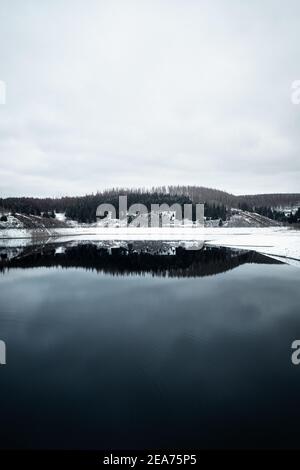 Schöne Aussicht auf einen See umgeben von Bäumen mit Schnee im Brocken Harz, Deutschland Stockfoto