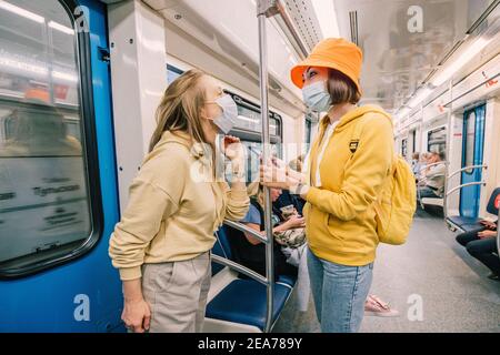 02. September 2020, Moskau, Russland: Zwei Freunde unterhalten sich lebhaft und scherzen in medizinischen Masken in der Moskauer Metro. Einschränkungen durch Coronavirus und Quarantäne Stockfoto