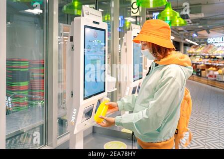 02. September 2020, Moskau, Russland: Frau in einer medizinischen Schutzmaske kauft eine Flasche frischen Saft an einer Selbstbedienungskasse im Supermarkt Stockfoto