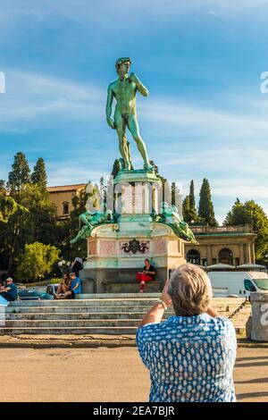 Ein Tourist fotografiert den Bronzeguss Davids, eine Kopie von Michelangelos Marmormeisterwerk, in der Mitte des Platzes Piazzale Michelangelo. Stockfoto